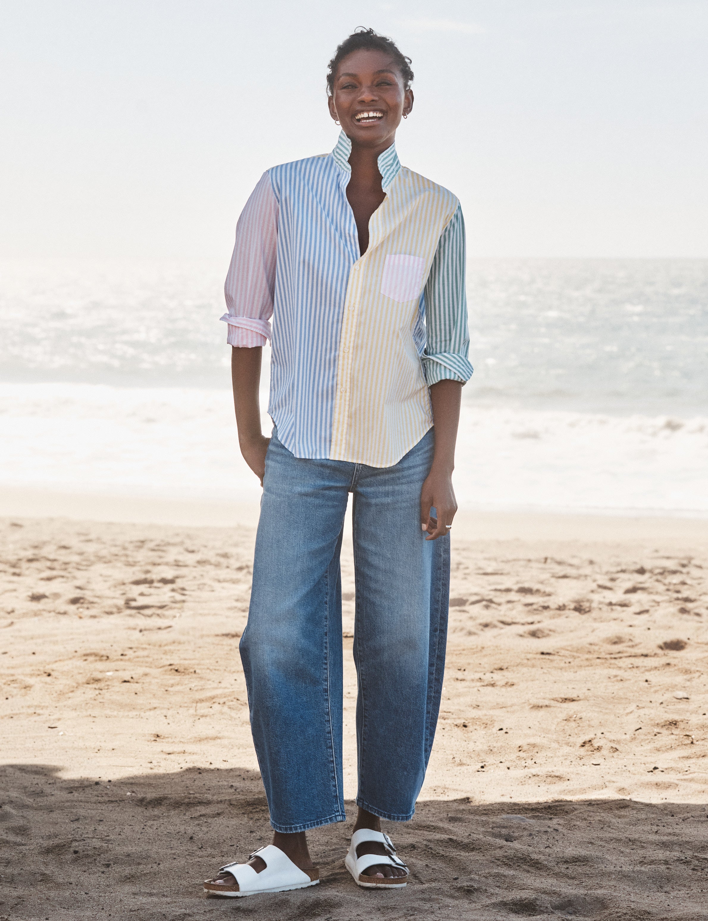 Woman standing on a beach wearing  a striped shirt and jeans., view 4