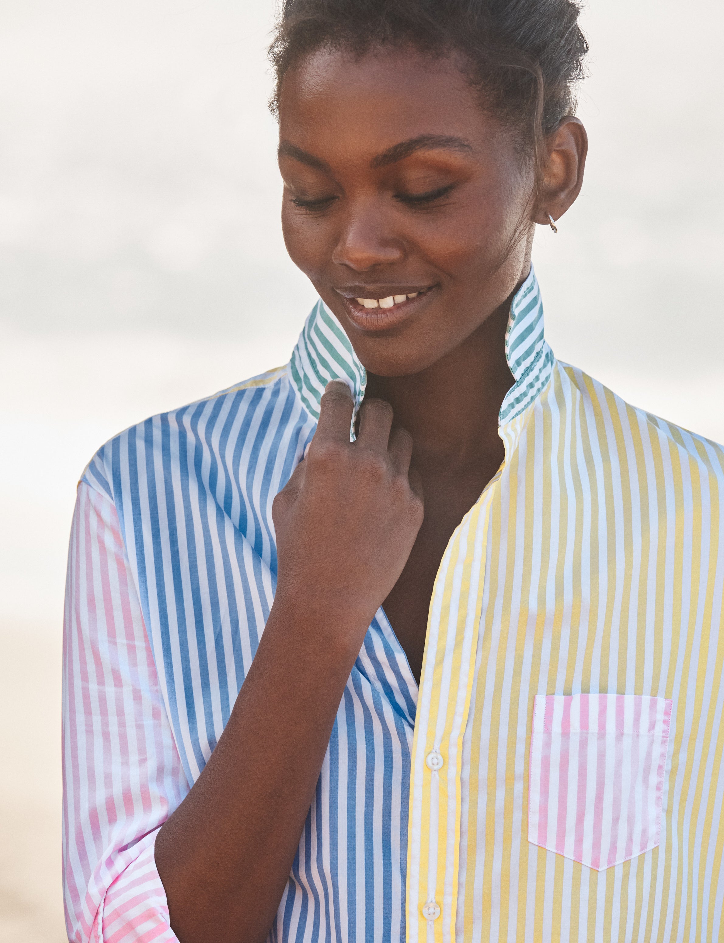 Woman wearing a colorful striped shirt with a neutral background, view 3