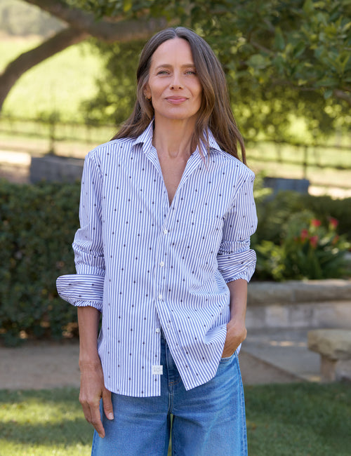 Woman wearing a blue and white striped shirt with rolled-up sleeves outdoors., front view