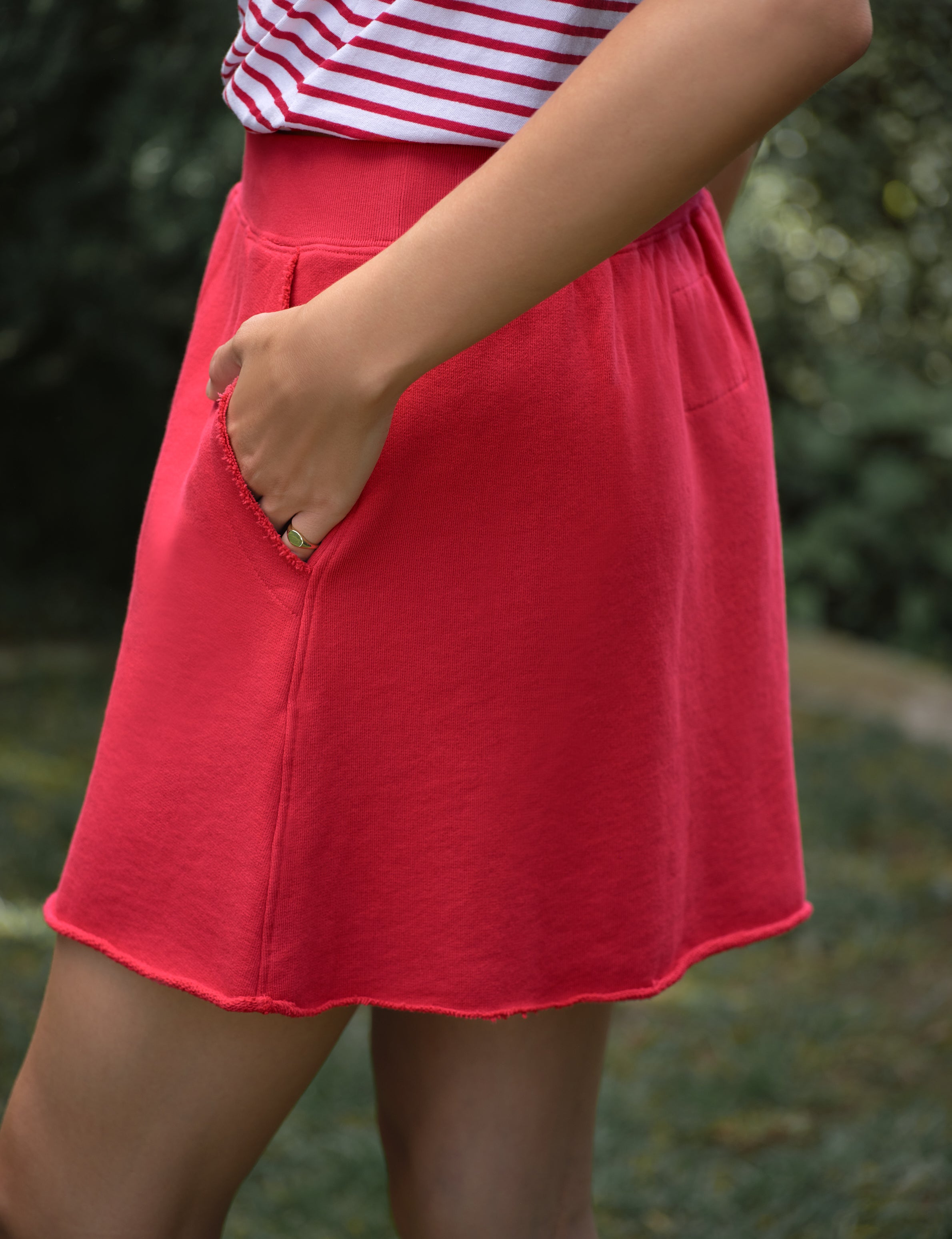 Red skirt worn by a person with a blurred green background, view 3