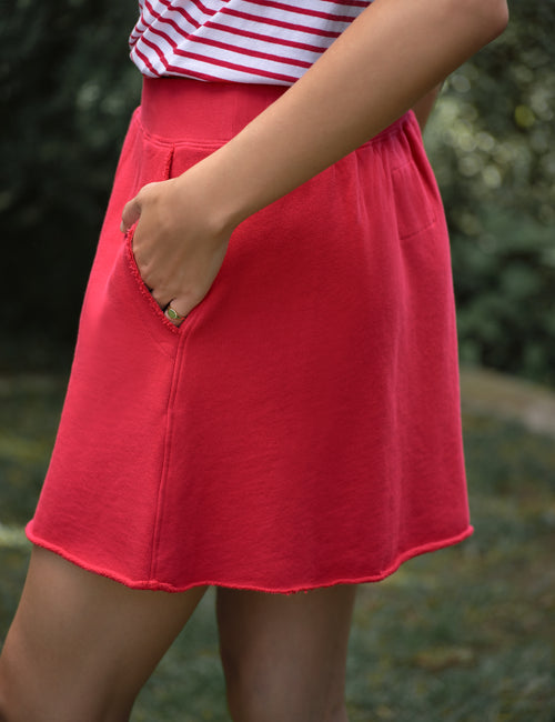 Red skirt worn by a person with a blurred green background, view 3