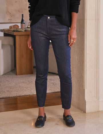 Person wearing dark blue glitter wax jeans and black shoes indoors.