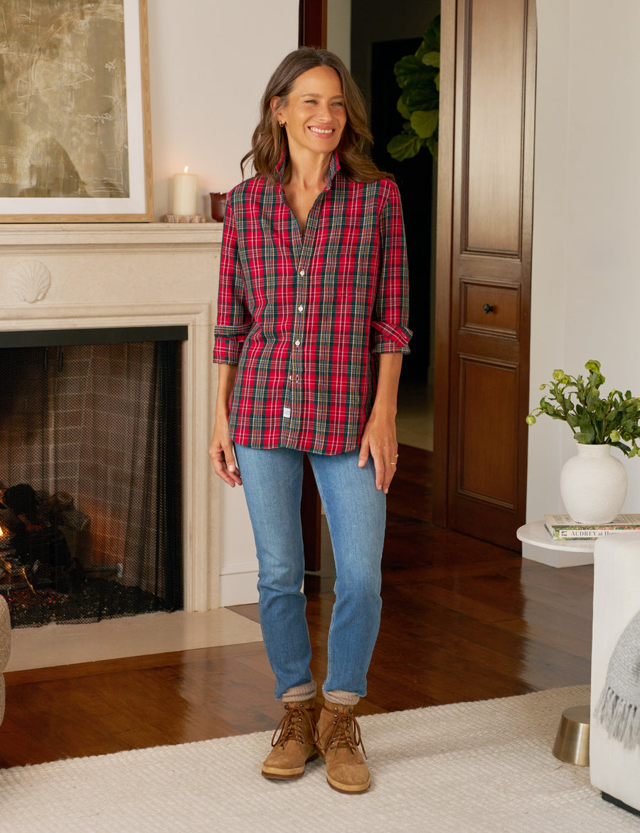 Woman wearing a plaid shirt, jeans, and boots in a cozy living room.