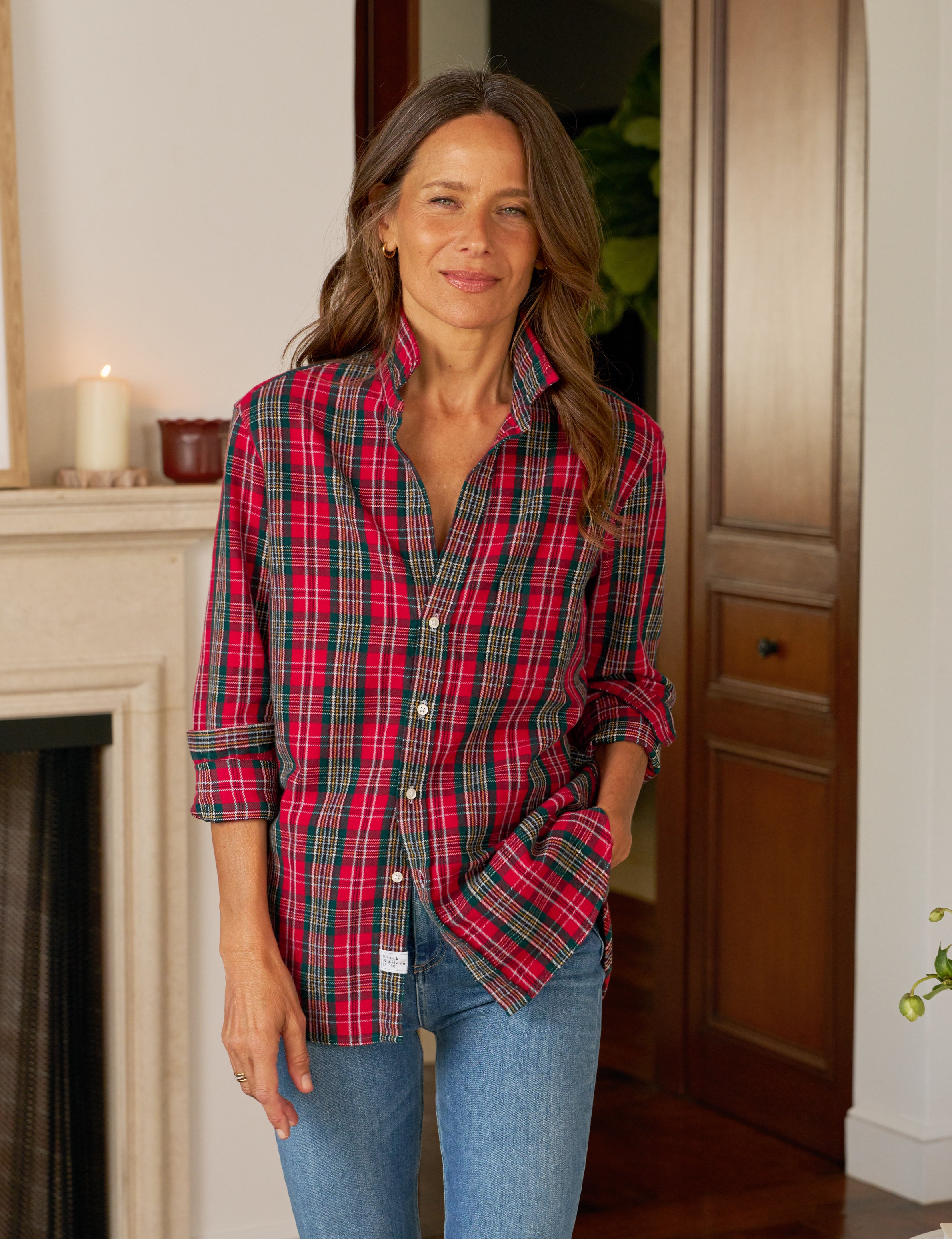 Woman wearing a red plaid shirt and blue jeans indoors.