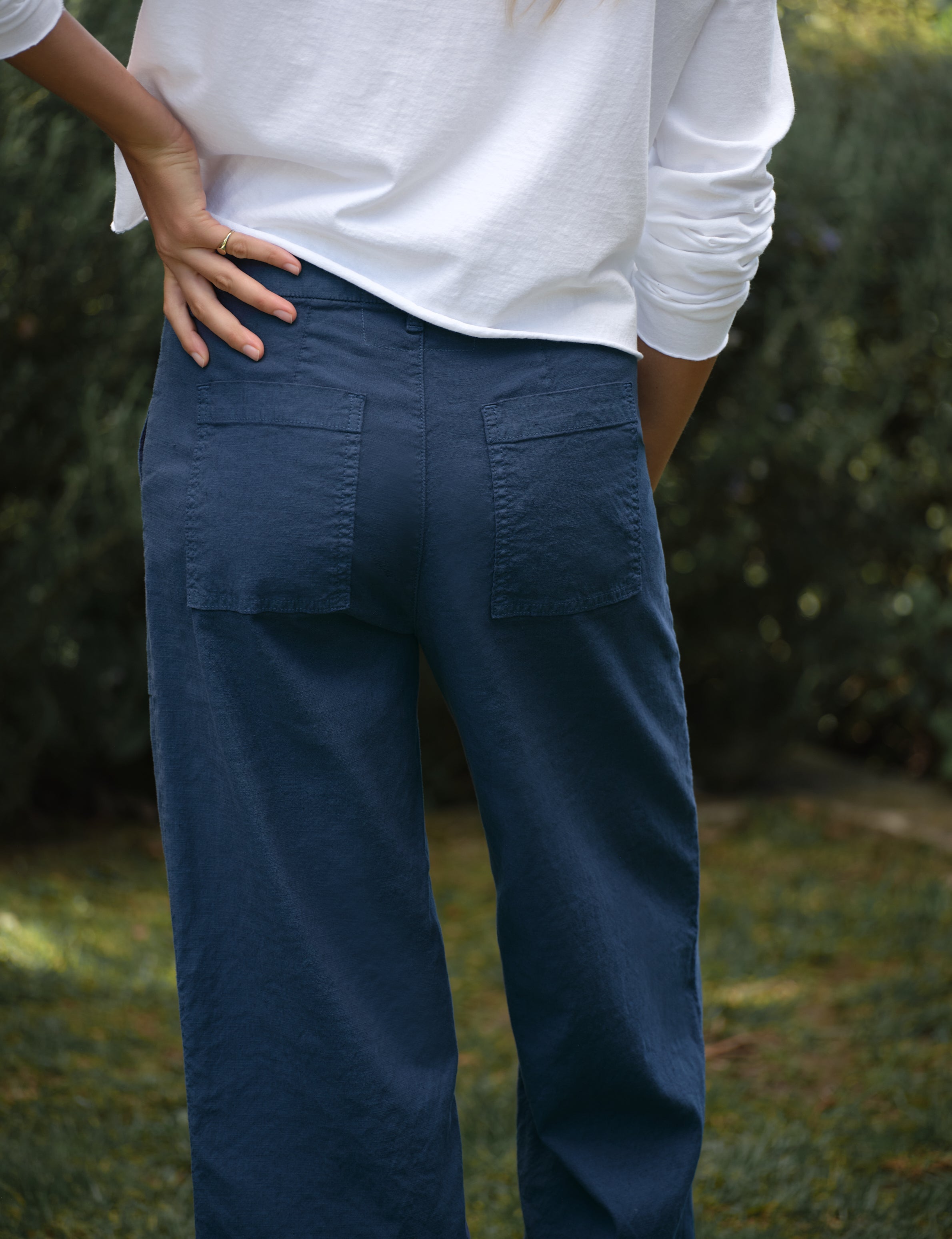Person wearing blue pants with a blurred natural background, view 3