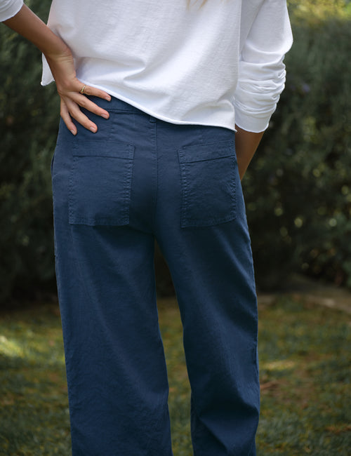 Person wearing blue pants with a blurred natural background, view 3