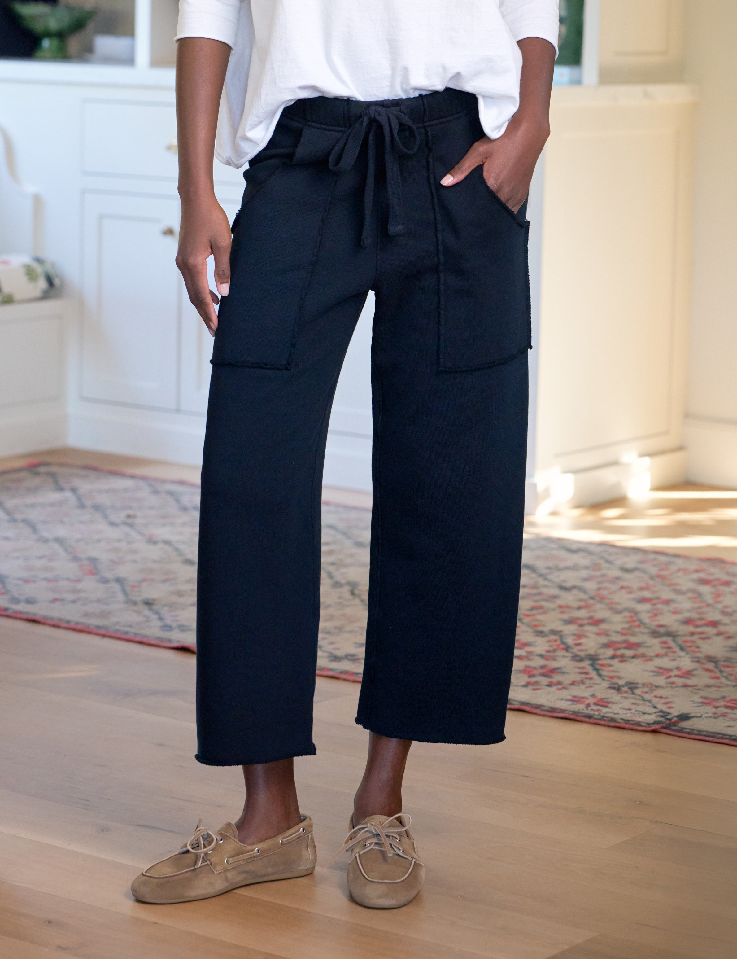 Person wearing navy wide-leg pants with a white shirt indoors.