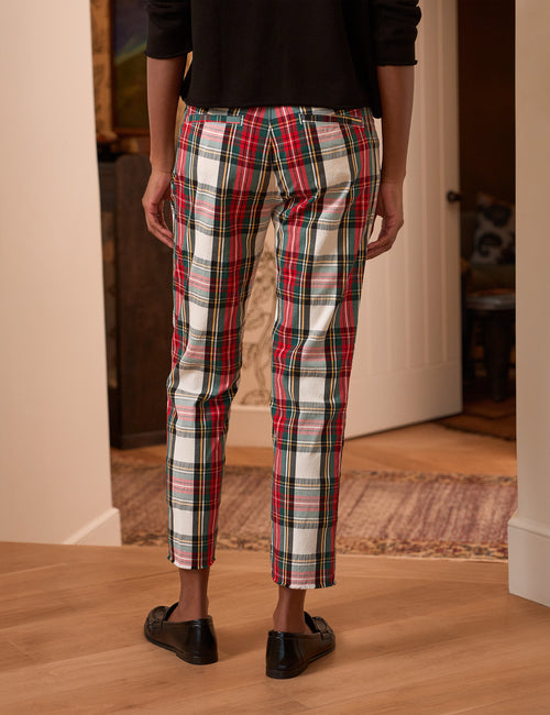 A person shown from the back wearing plaid cropped pants with a red, green, black, and white tartan pattern, paired with a black top and black loafers in an indoor room setting., alternate view