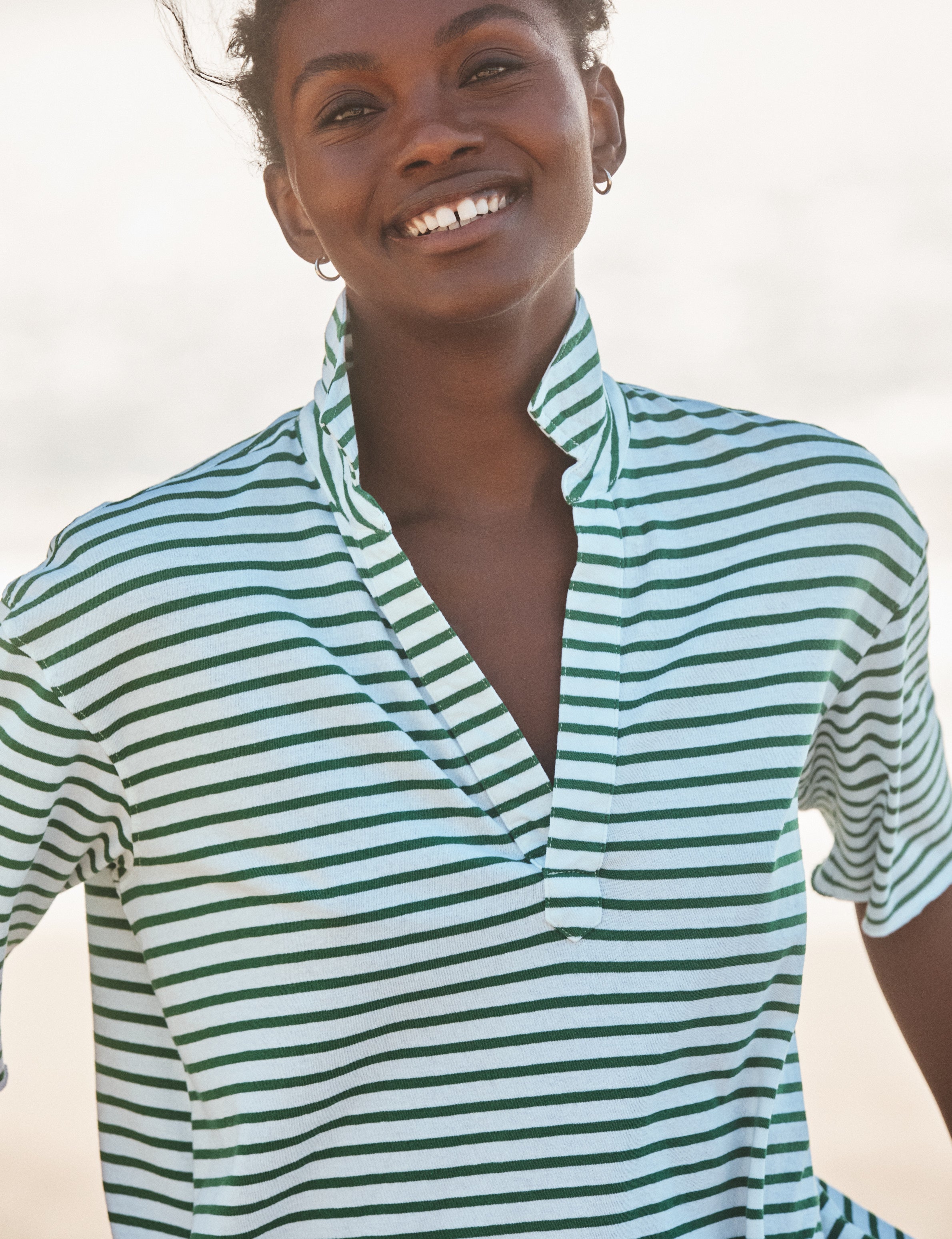 Woman wearing a green and white striped shirt against a neutral background, view 3