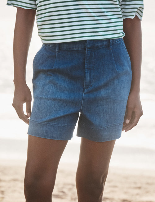 Person wearing blue denim shorts on a beach, front view