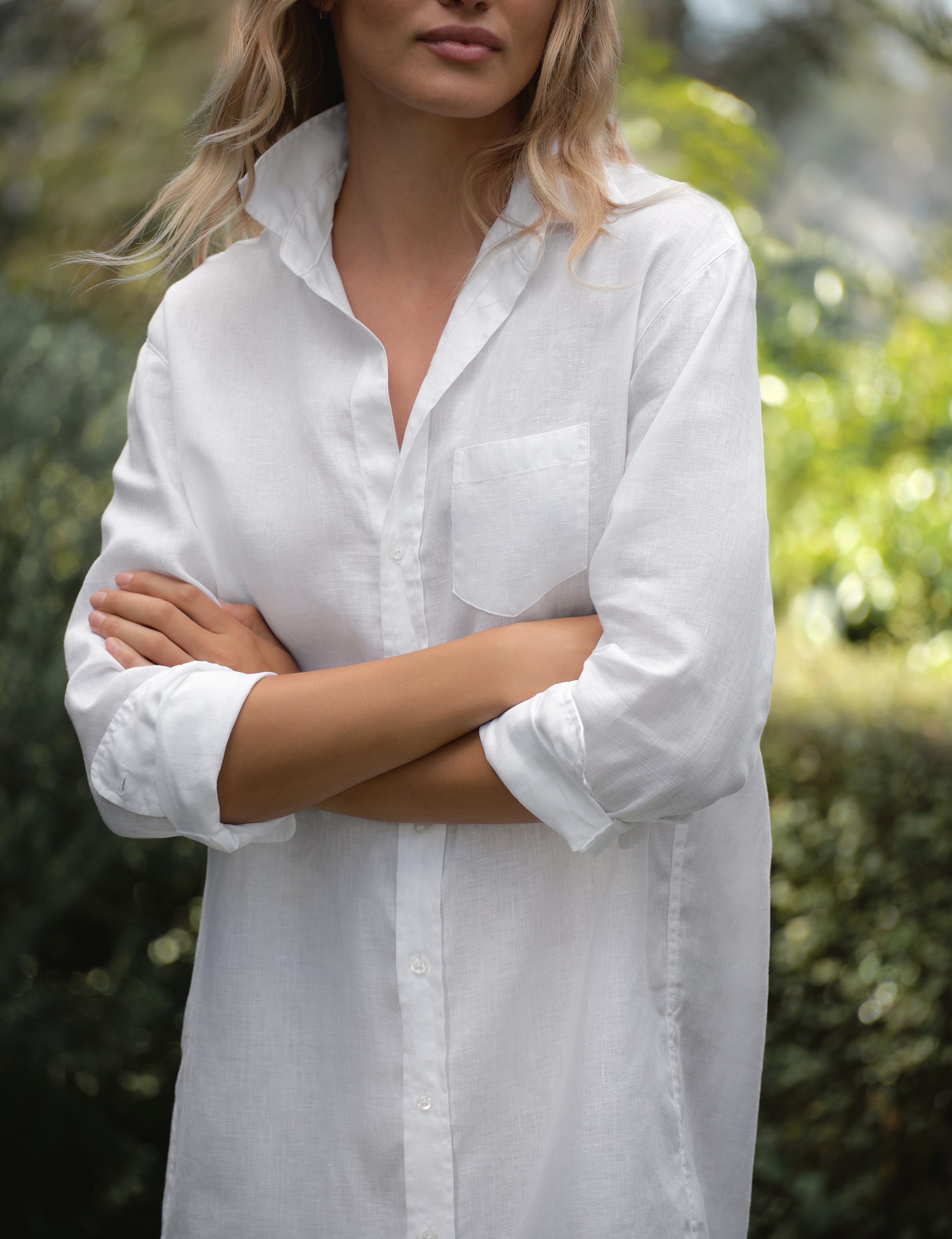 Person wearing a white dress with a blurred natural background, view 3