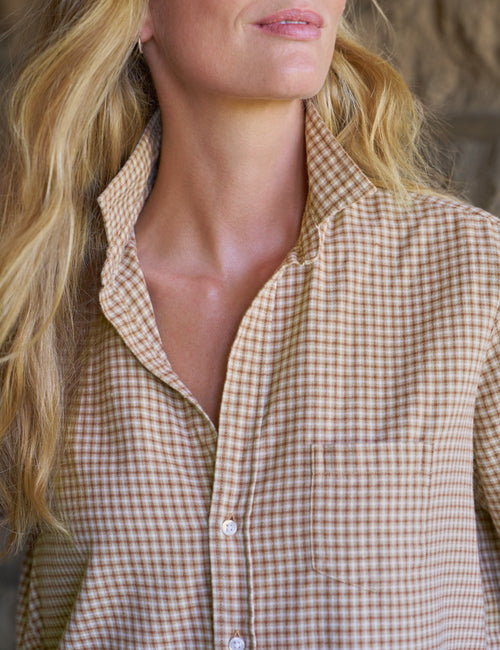 Close-up of a woman wearing a tan and white gingham button-down shirt, showing her neck, lower face, and the collar and chest area of the shirt., view 3
