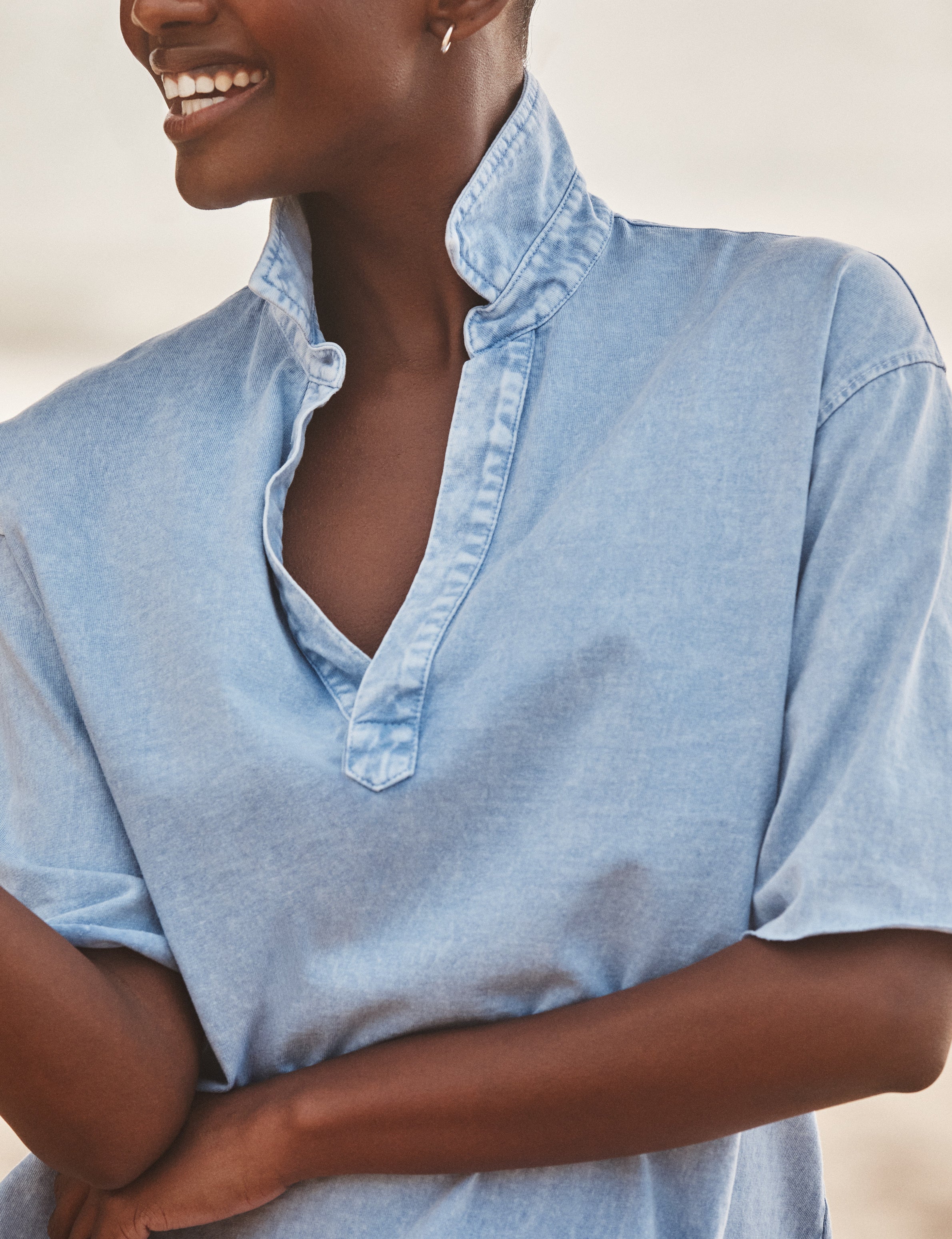 Woman wearing a light blue shirt with a neutral background, view 3