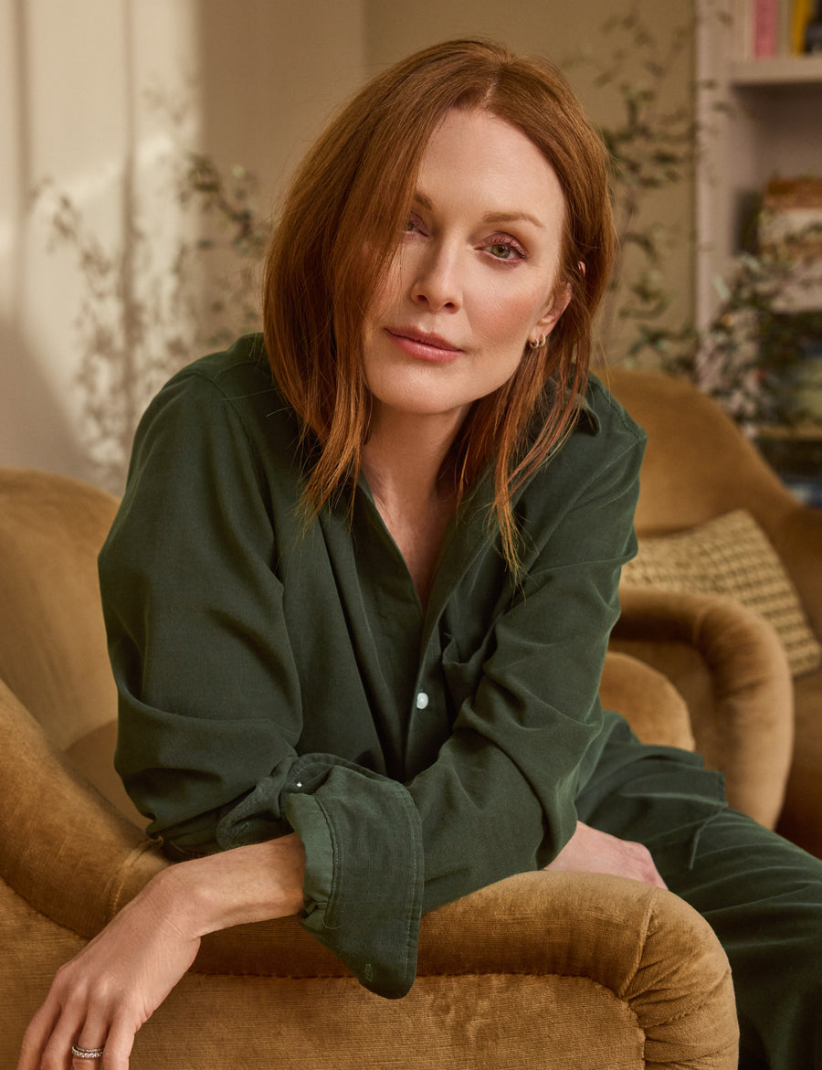Woman sitting on a brown couch wearing a green shirt in a cozy room.