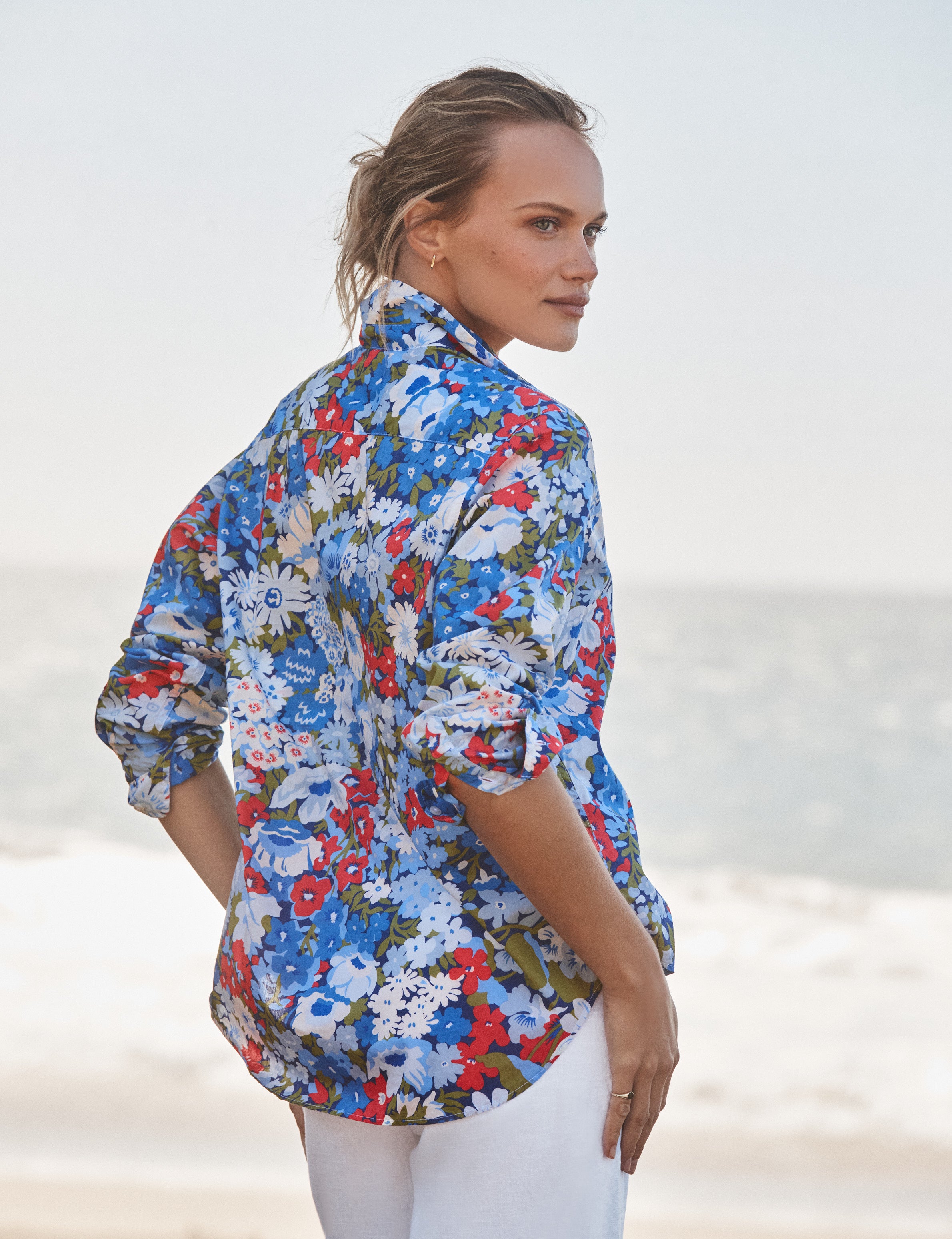 Woman wearing a colorful floral shirt on a beach, alternate view