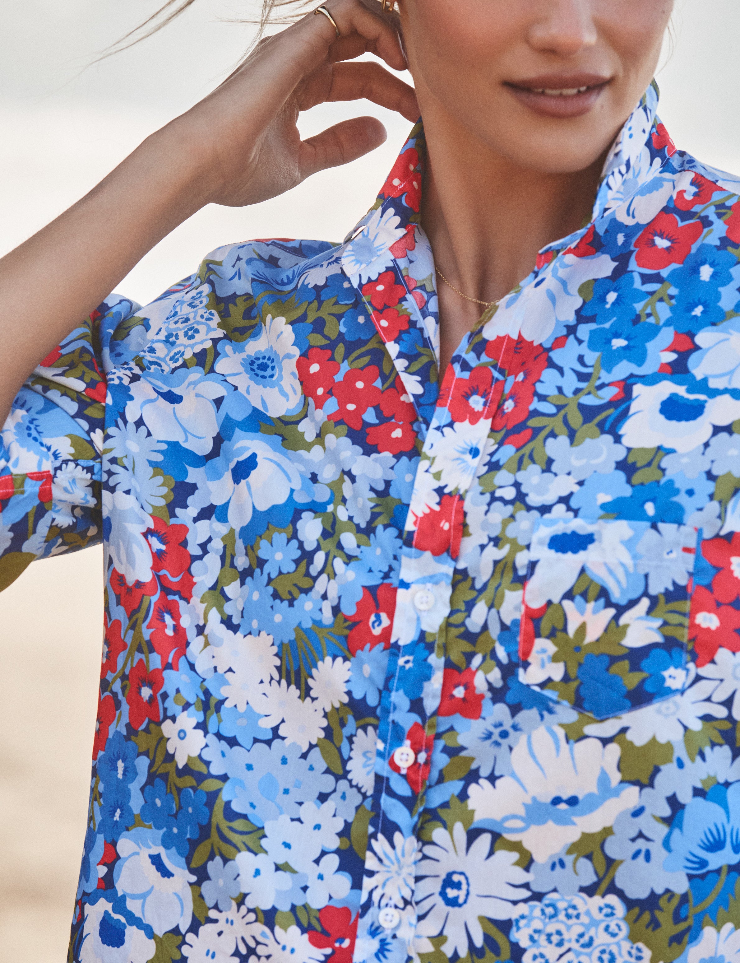 Person wearing a colorful floral shirt with a neutral background, view 3