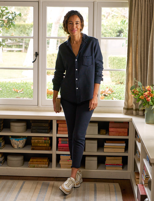 Woman standing in a room with large windows and bookshelves., front view