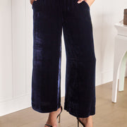 Person wearing navy velvet wide-leg pants and black high-heeled sandals in a minimal indoor setting.