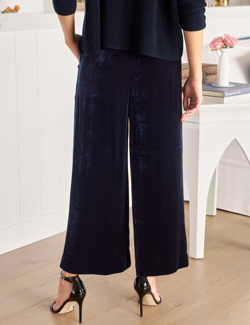 Person wearing navy wide-leg pants in a minimal indoor setting, alternate view