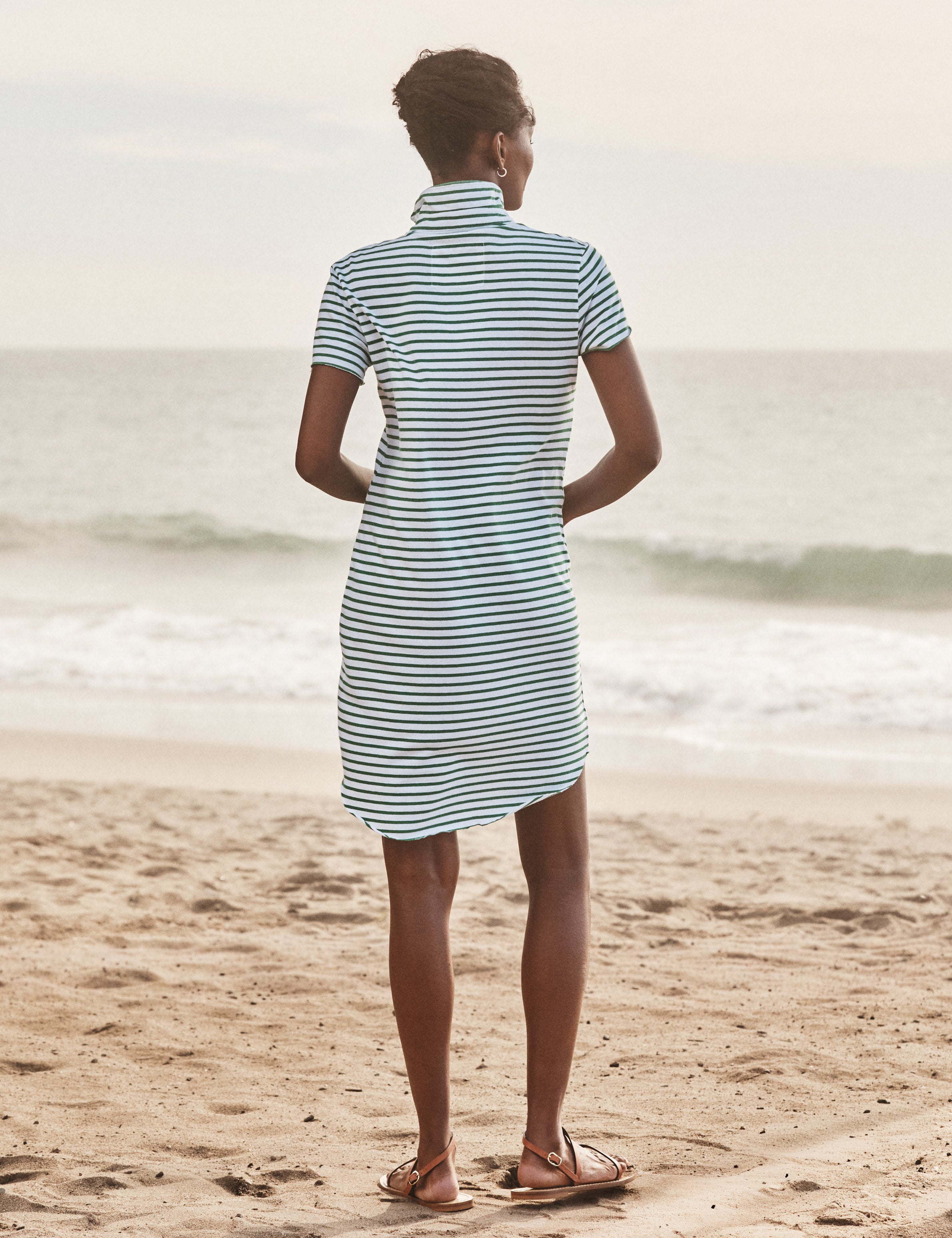 Person wearing a striped dress standing on a beach, alternate view
