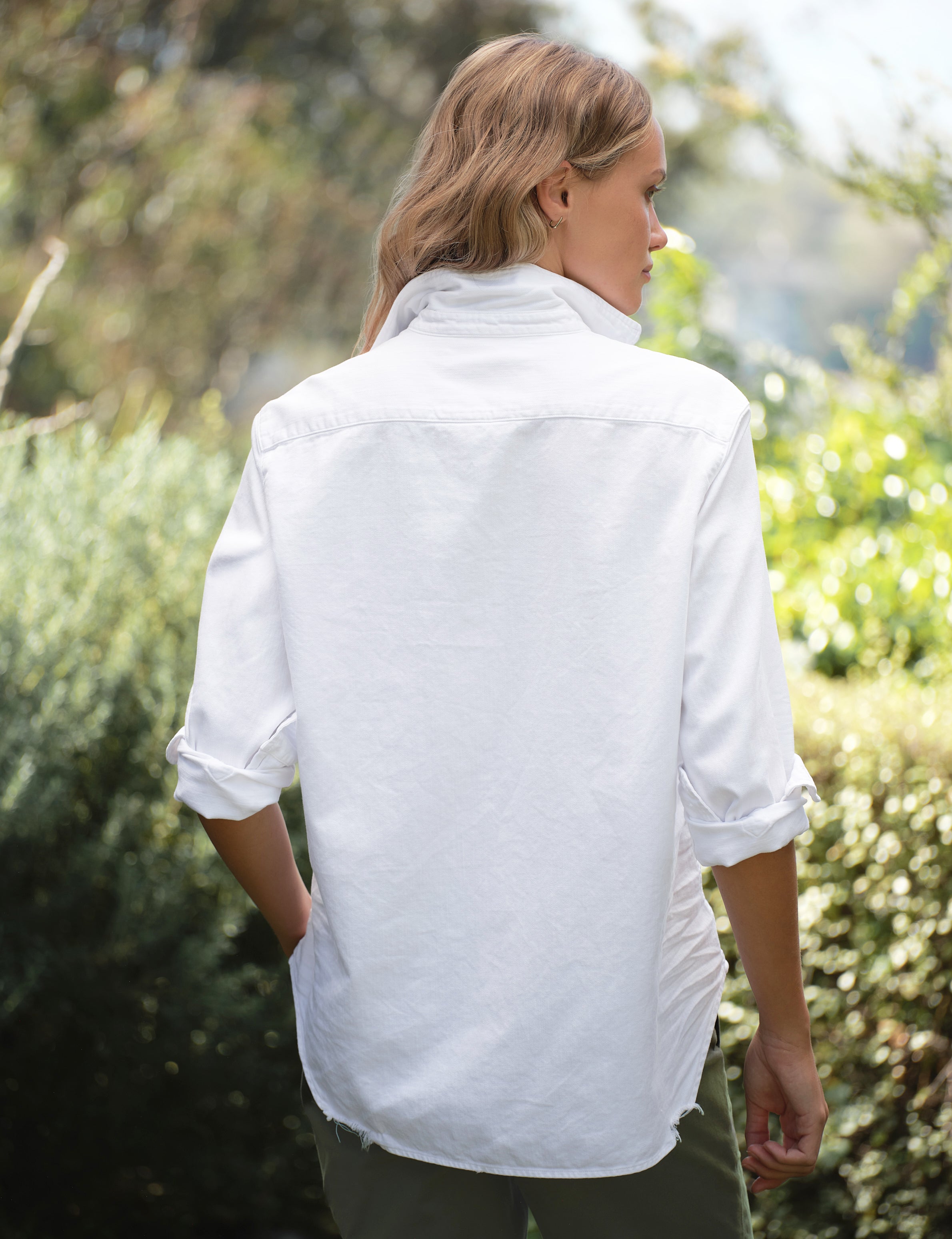 Person wearing a white shirt standing in a garden, alternate view