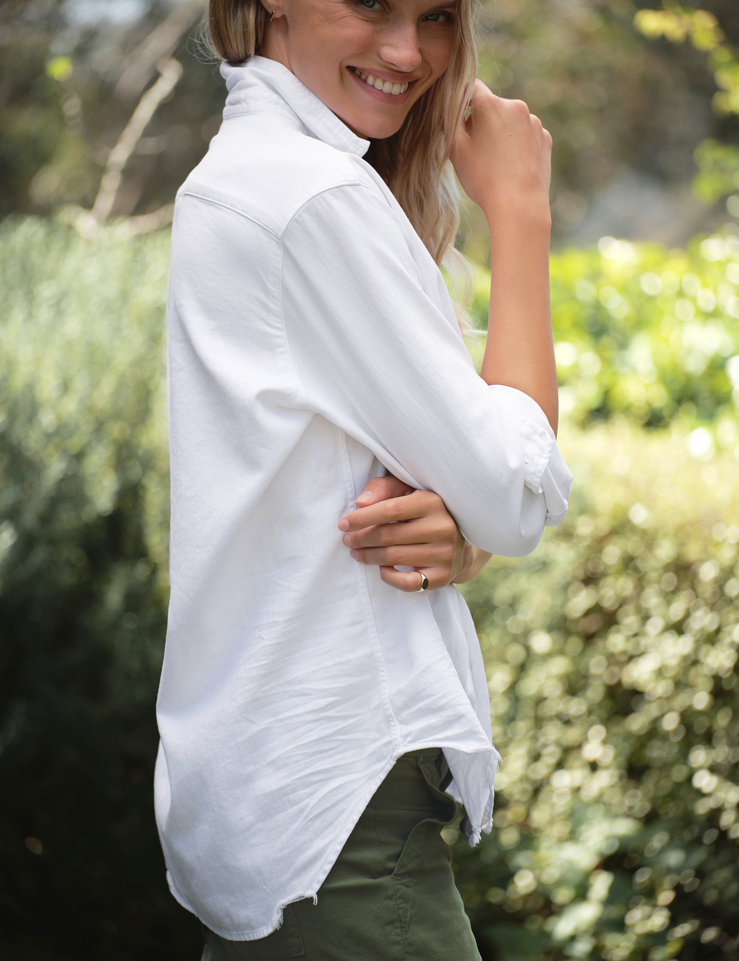 Woman wearing a white shirt with a blurred natural background, view 3