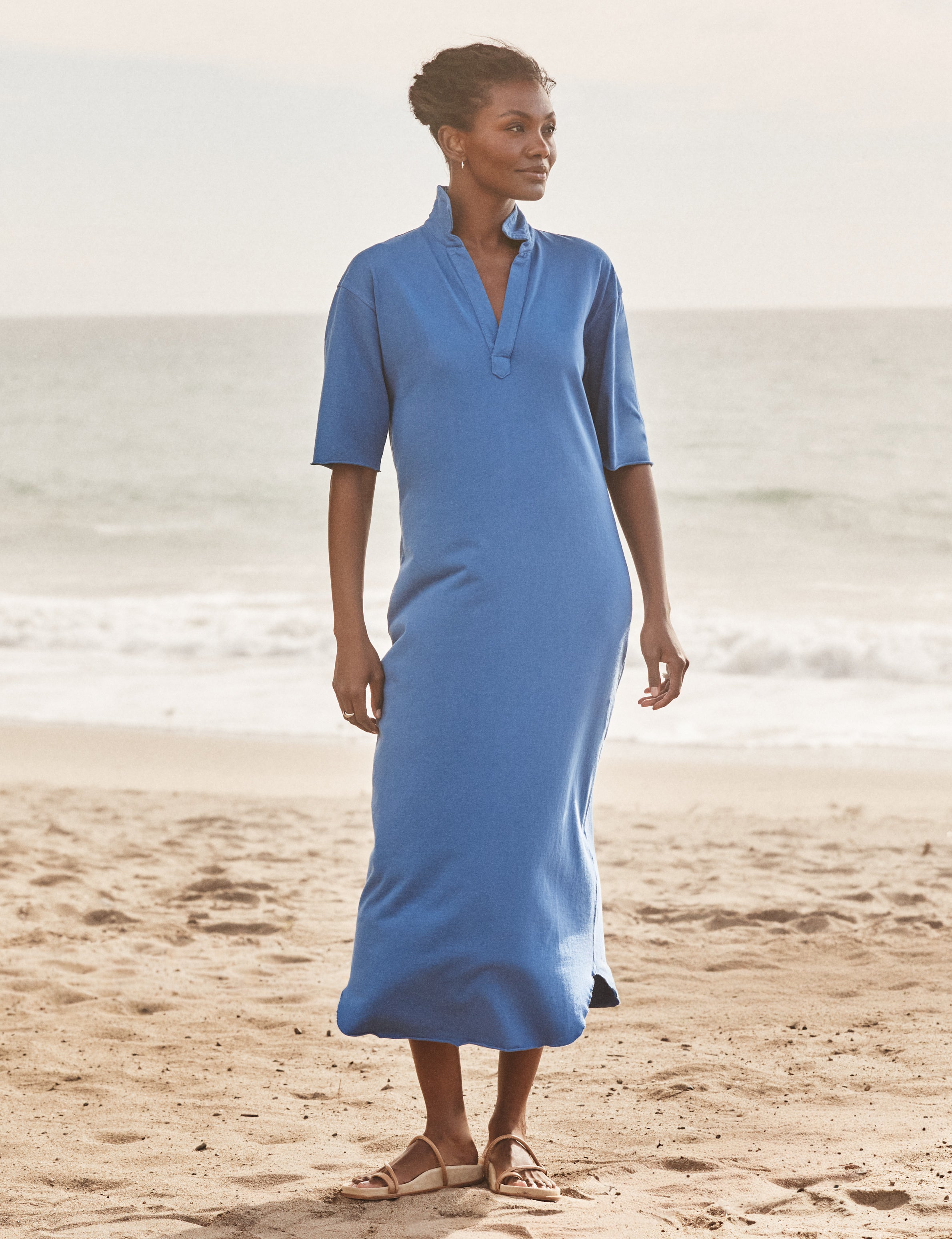 Woman wearing a blue dress standing on a beach, front view