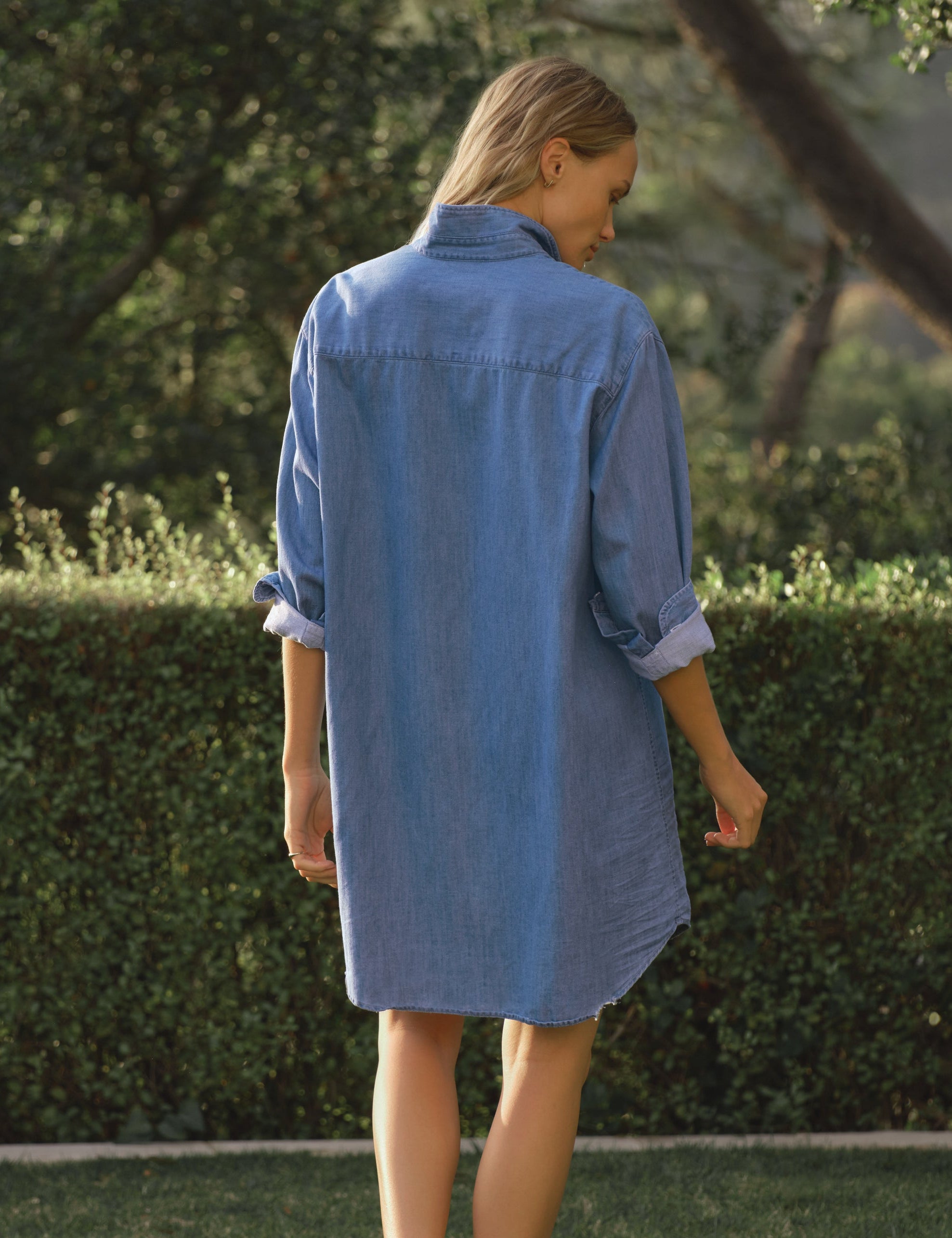 Woman wearing a blue dress standing in a garden, view 3