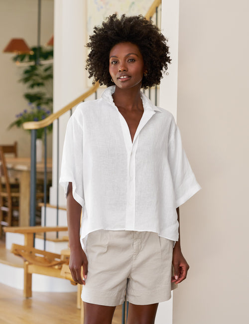 Woman wearing a white shirt and beige shorts indoors, front view