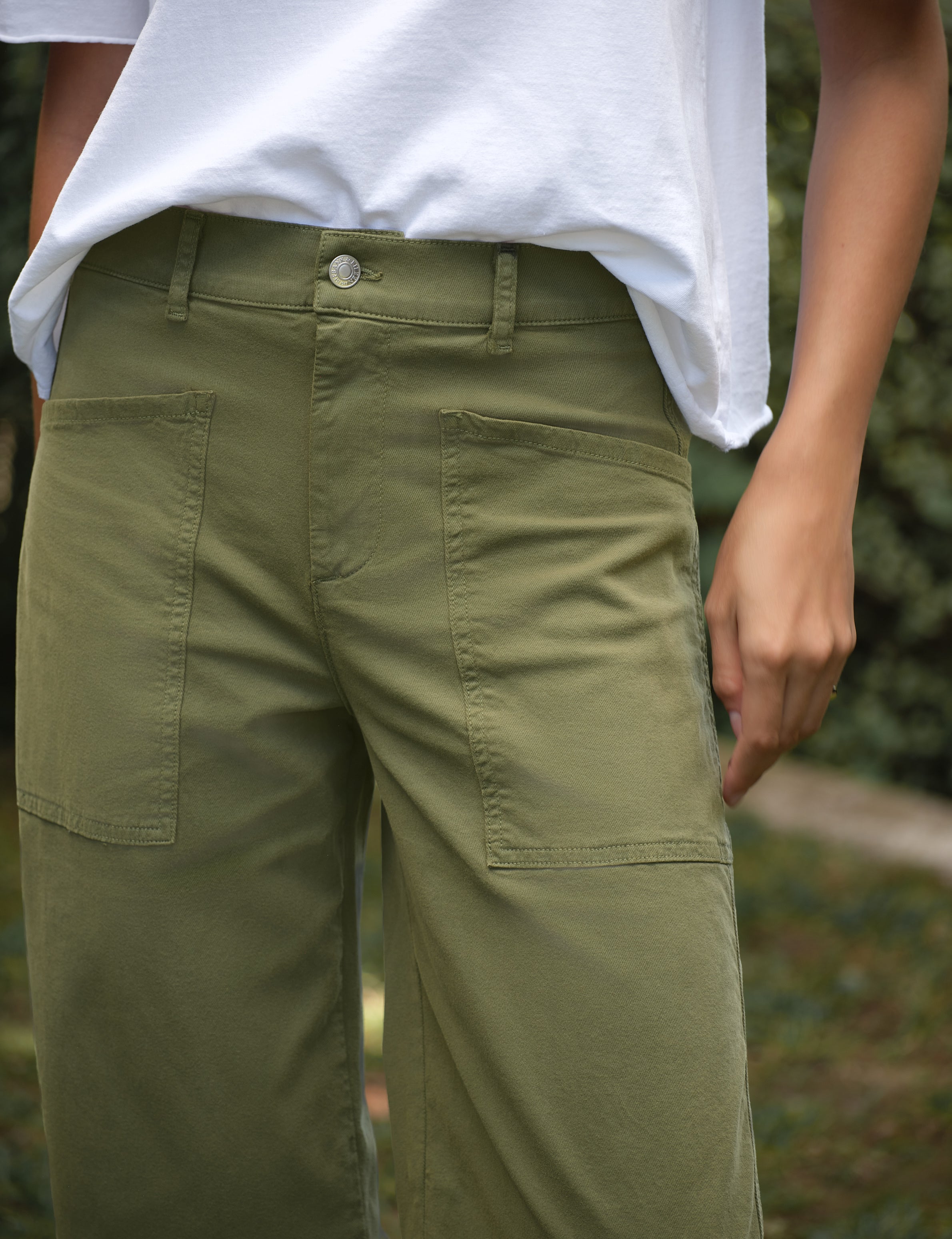 Person wearing green pants with a blurred natural background, view 4