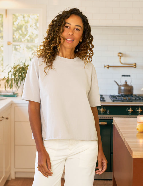 Woman standing in a kitchen wearing a white shirt and pants., front view