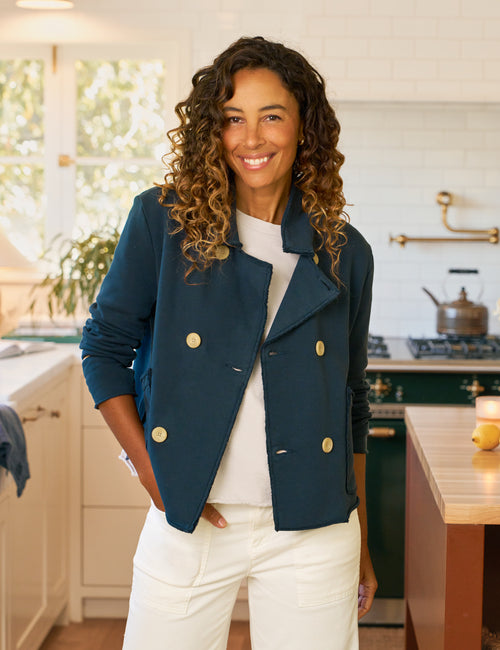 Woman wearing a navy blue jacket with gold buttons in a kitchen., front view