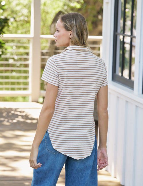 Woman wearing a striped shirt and blue jeans standing outdoors., alternate view