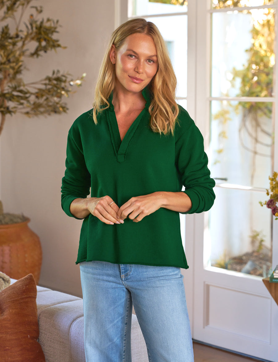 Woman wearing a green blouse and blue jeans indoors