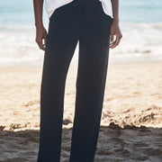 Person wearing navy pants and a white shirt on a beach