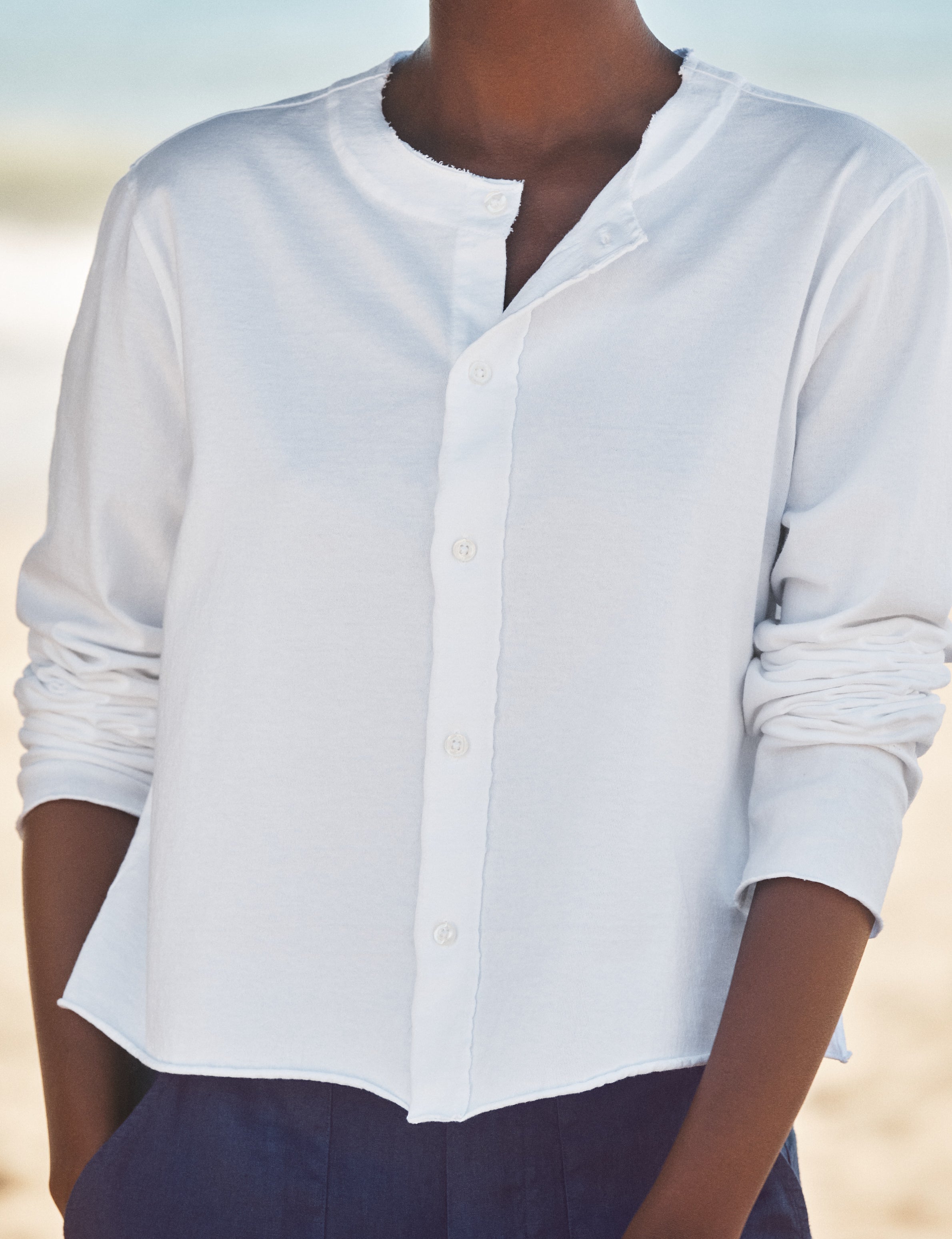 Person wearing a white button-up shirt with a blurred background, view 3