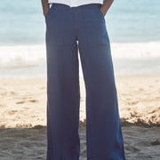 Person wearing blue wide-leg pants and a white shirt on a beach.