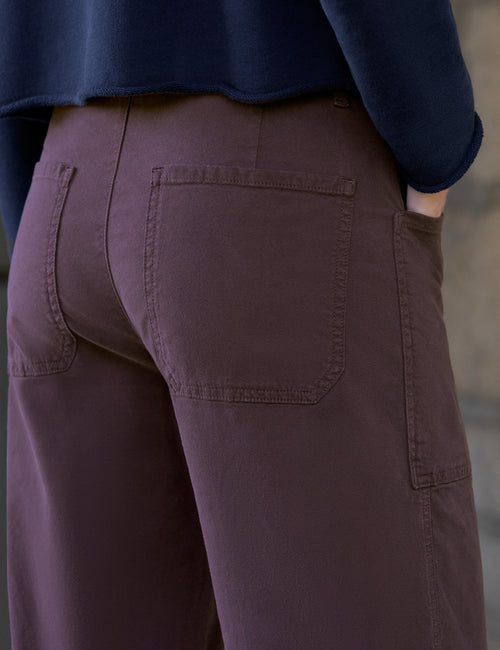 Close-up back view of a person wearing dark brown pants with a navy blue top, showing the back pockets and fabric texture., view 4