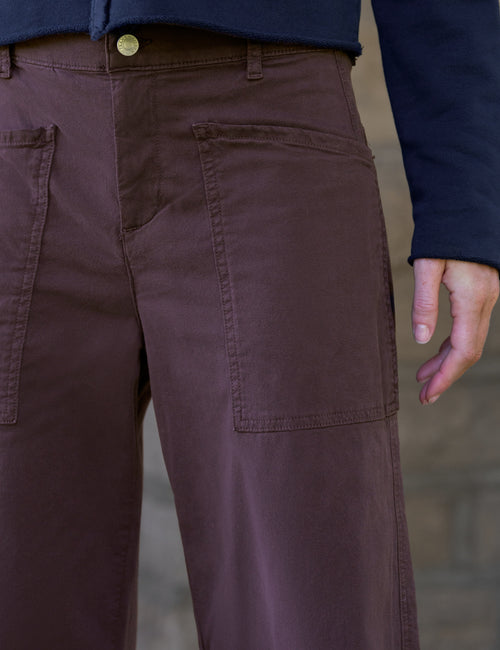Close-up of a person wearing dark brown barrel-leg pants with a navy blue jacket, showing the back pocket and waistband., view 3