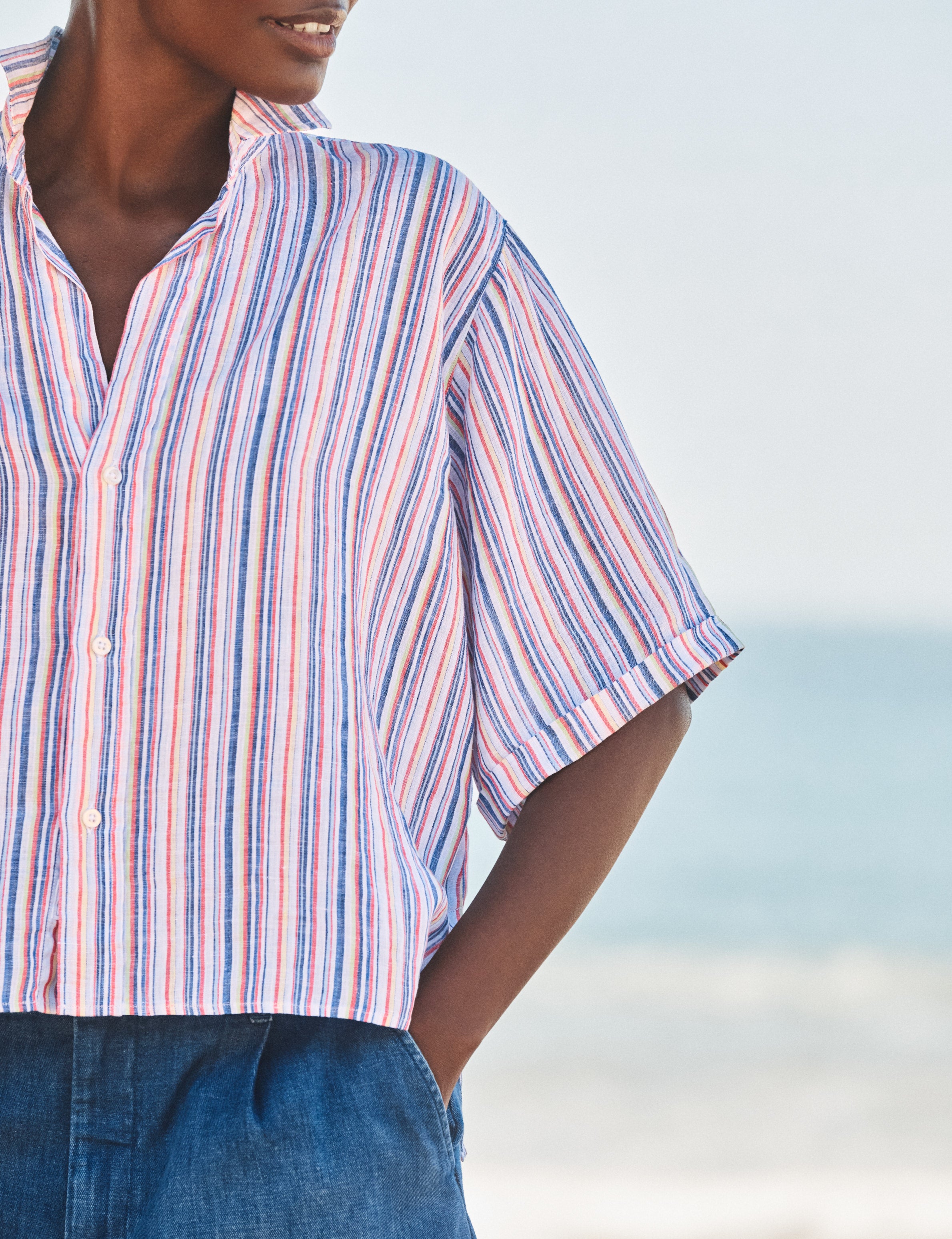 Person wearing a striped shirt with a blurred beach background, view 3
