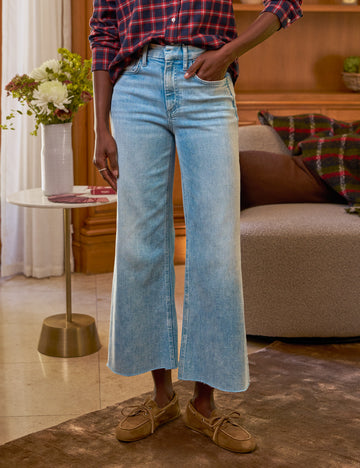 Person wearing blue jeans and a plaid shirt in a living room setting