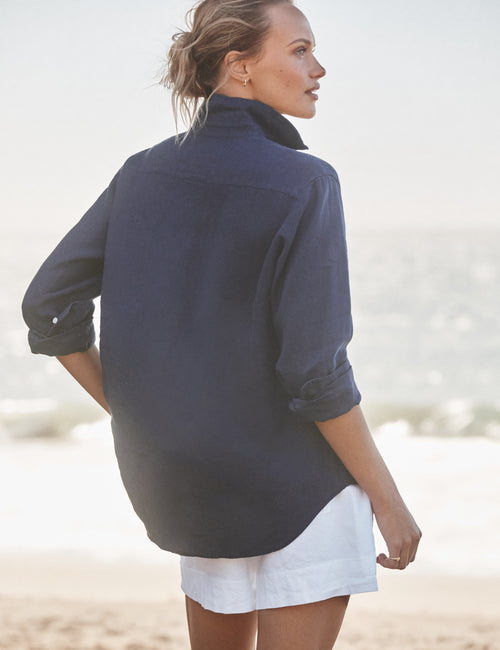 Woman wearing a navy blue shirt on a beach, alternate view