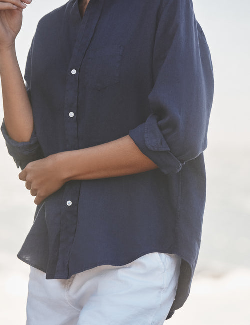 Person wearing a navy blue shirt with rolled-up sleeves on a white background, view 3
