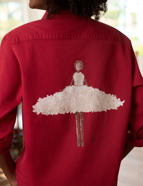 A person viewed from behind wearing a red button-up shirt with a large white ballerina figure printed across the back., view 3