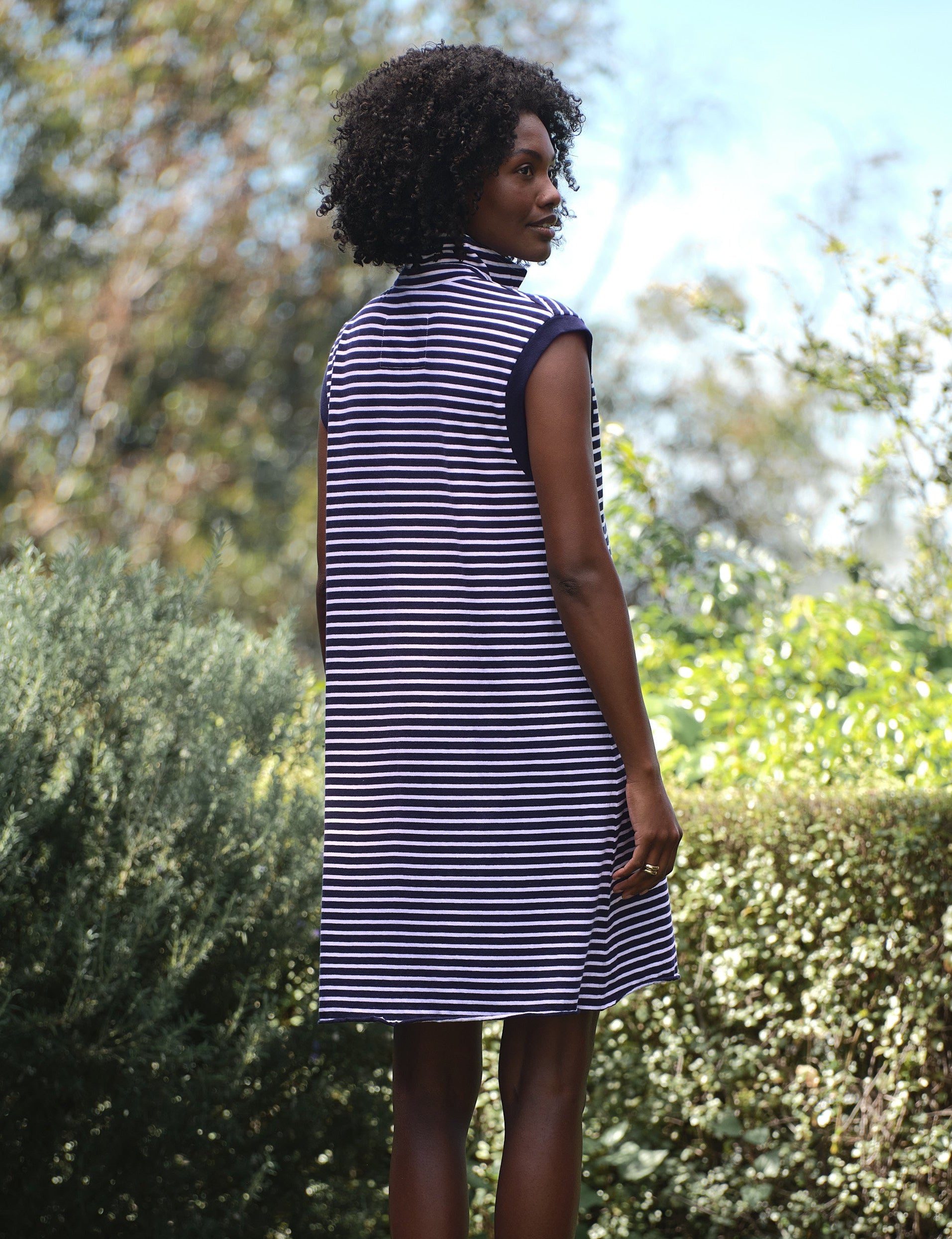 Woman wearing a striped dress standing in a garden, alternate view