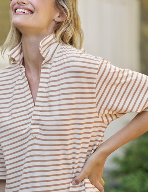 A close-up of a woman wearing a short-sleeve collared dress with horizontal beige and brown stripes, smiling outdoors., view 3