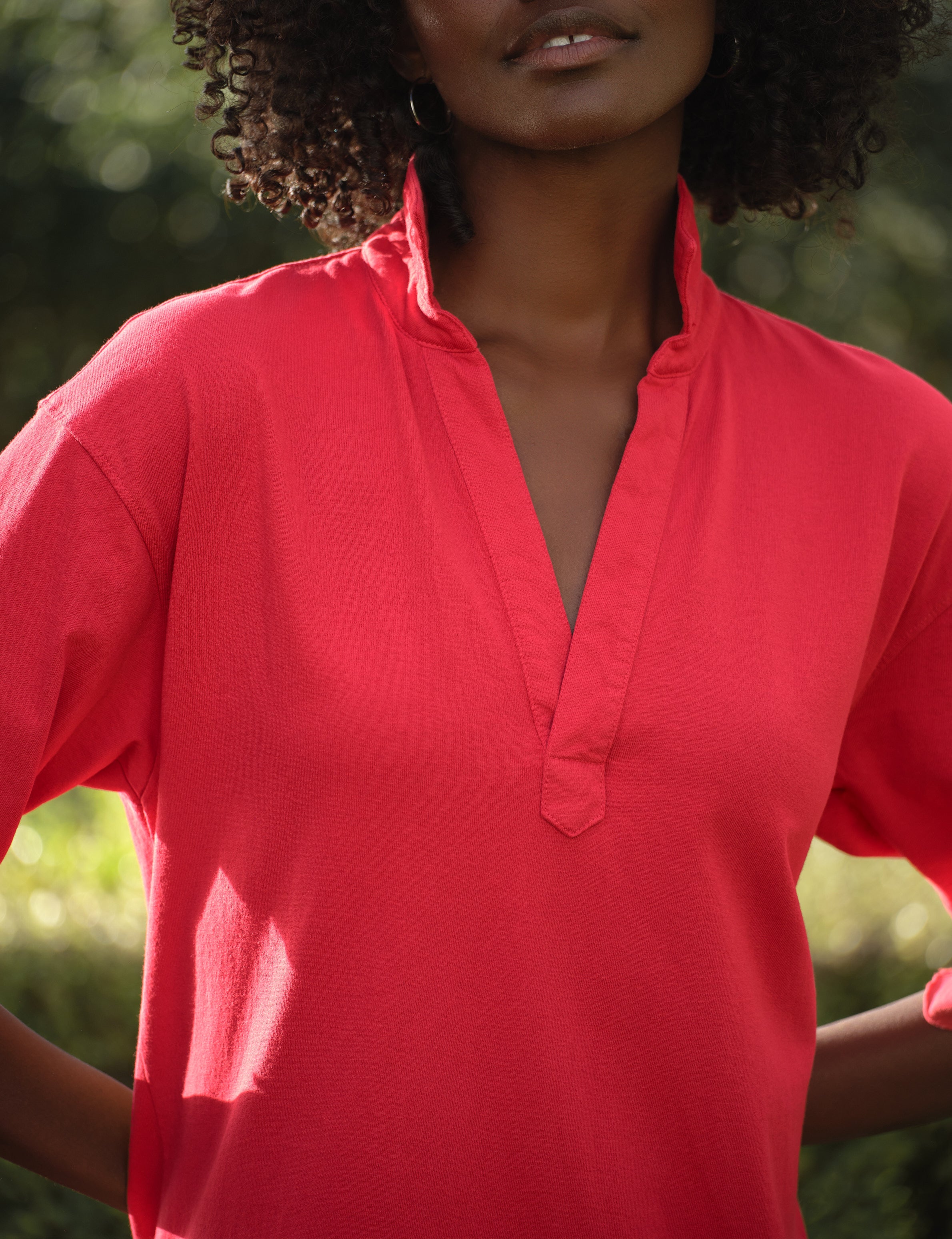 Person wearing a red shirt with a blurred green background, view 3
