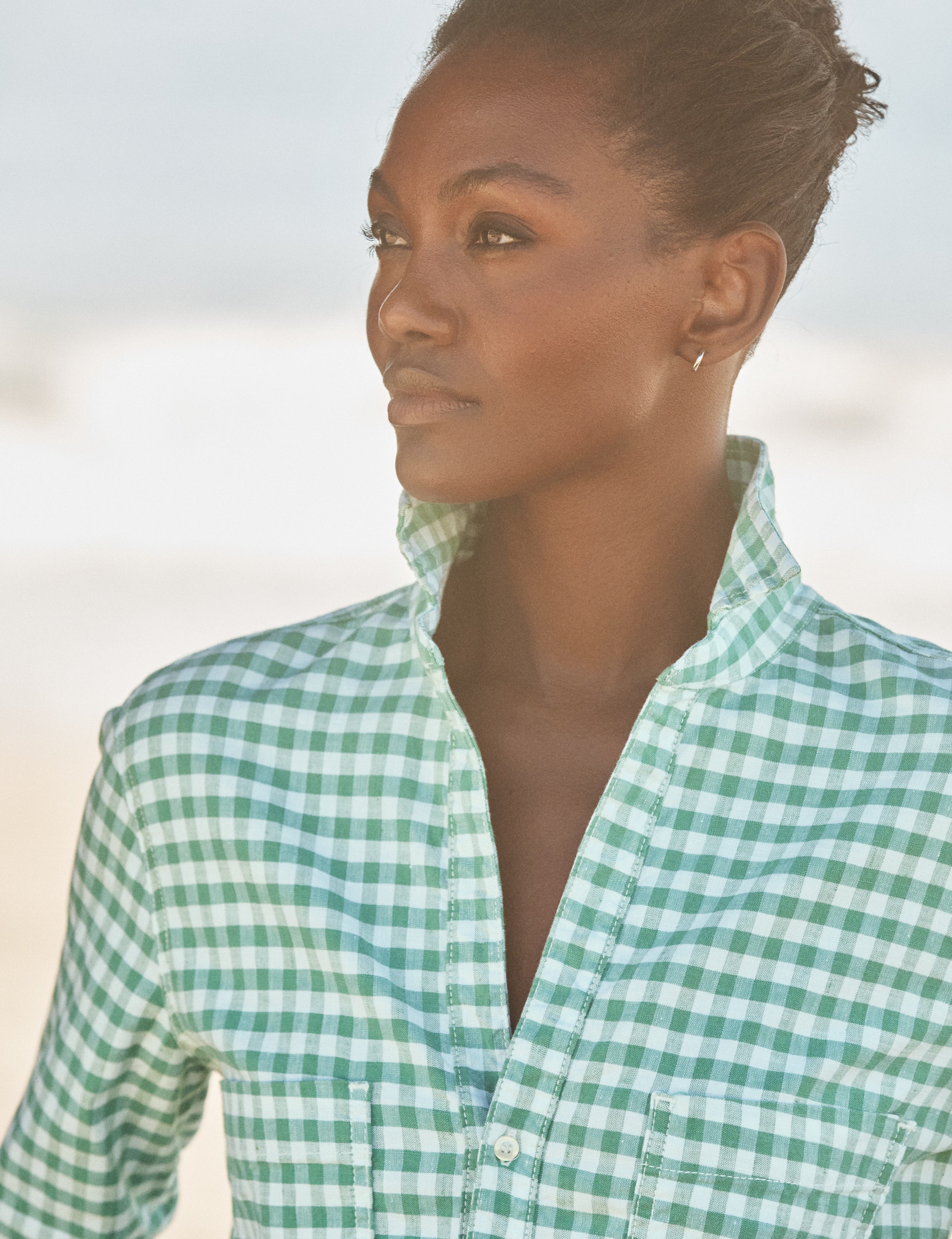 Woman wearing a green and white checkered shirt against a blurred natural background, view 3