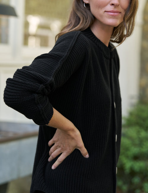Woman wearing a black sweater with a blurred background, alternate view