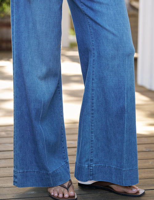 Blue jeans worn by a person on a wooden deck, view 3